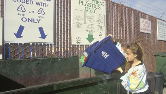 Woman in the 1990's bringing recycling to a dropoff location where she has to sort it herself.