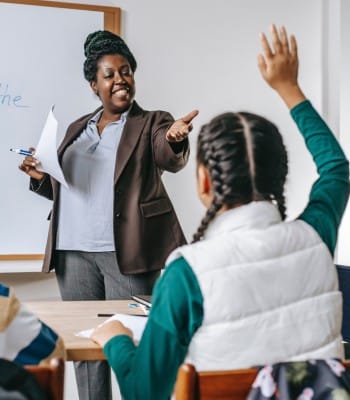 Teacher calling on a student with raised hand during a classroom presentation